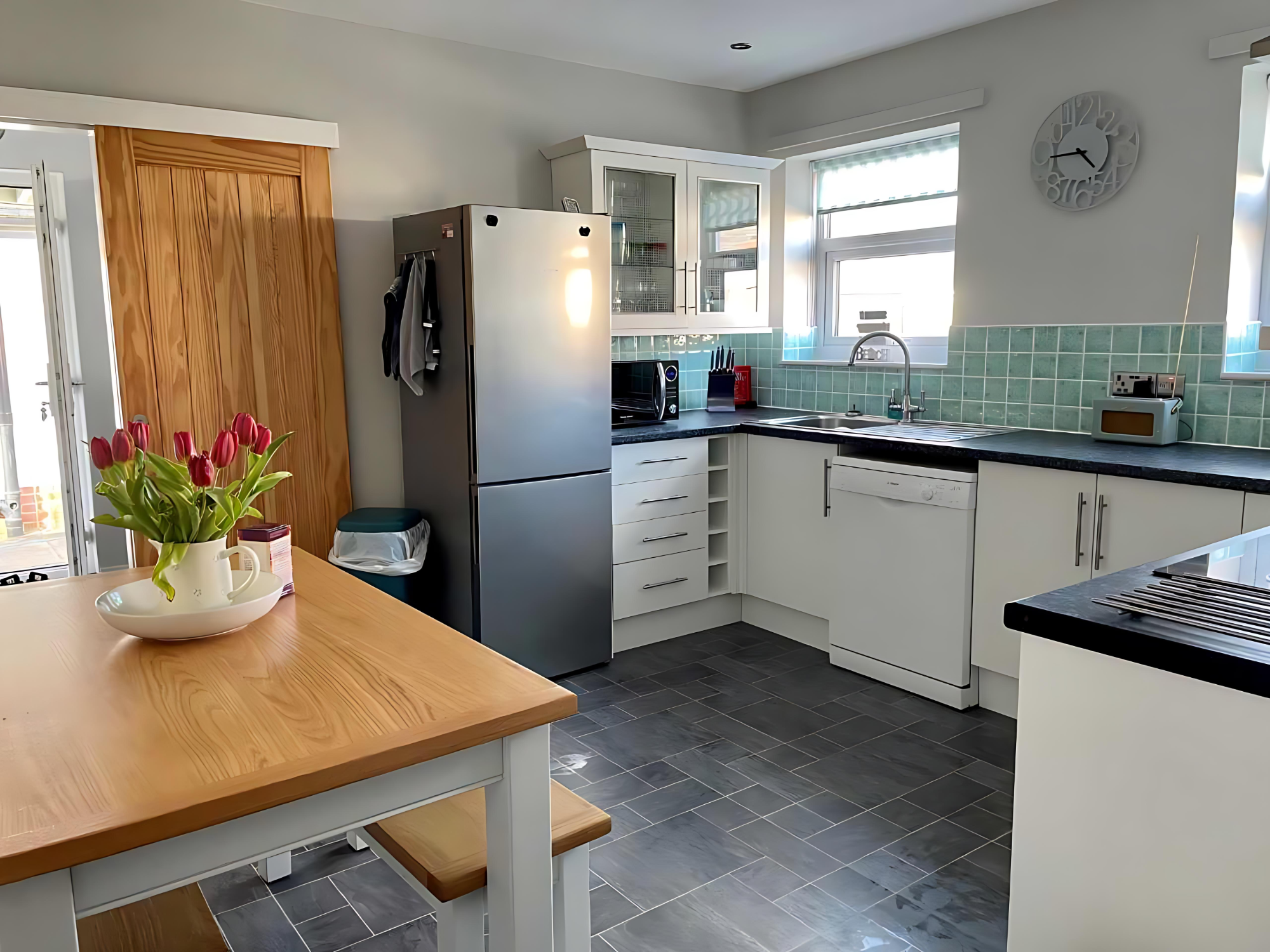 Marram Cottage Beadnell Kitchen Bright kitchen featuring a wooden table, modern appliances, and a vase of flowers.